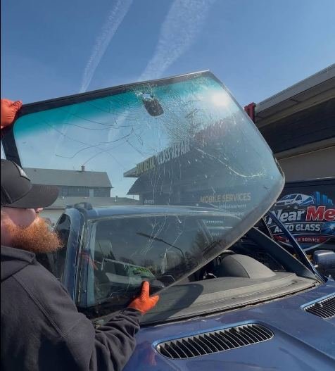 Technician installing a windshield beside the Near Me Auto Glass van